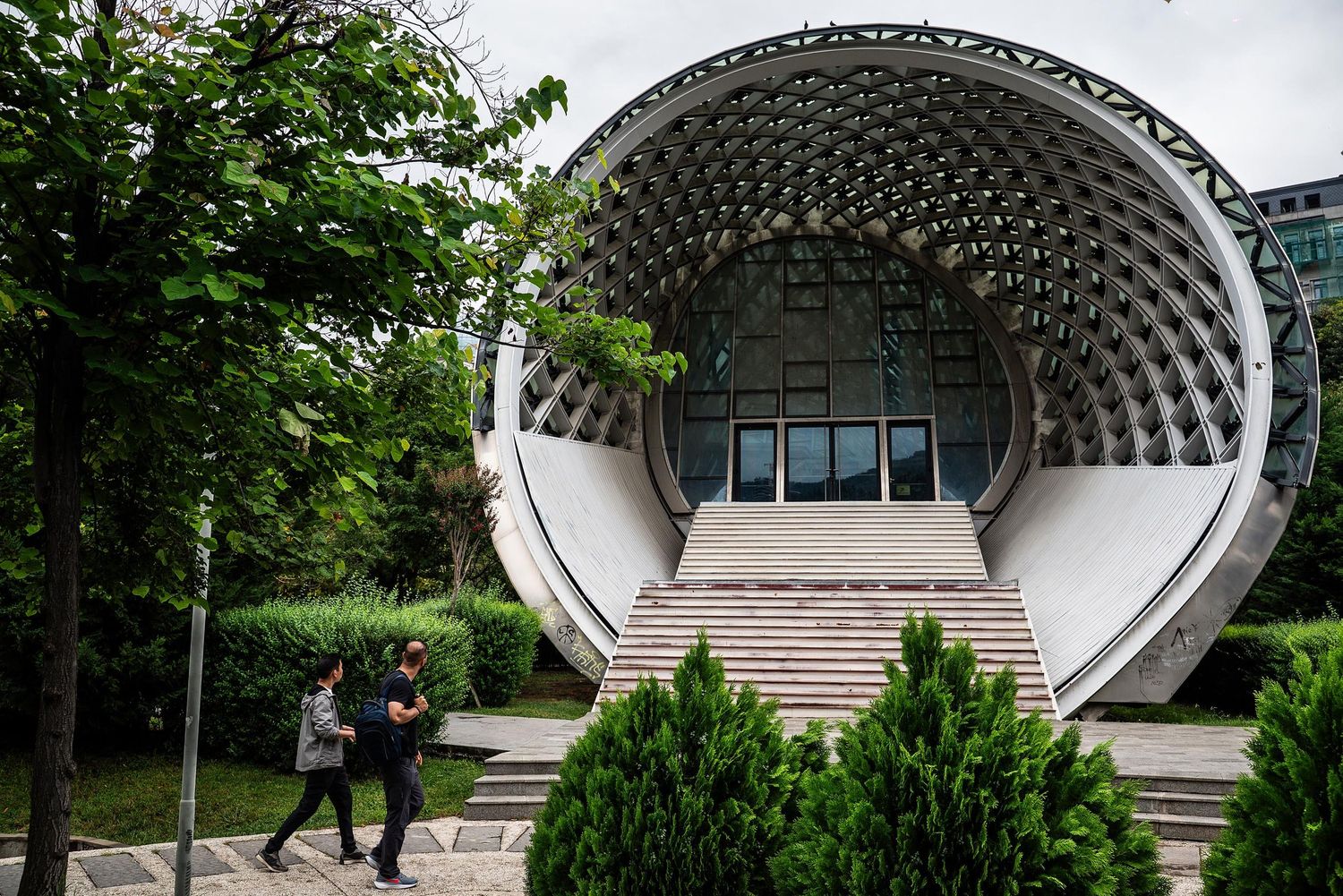 Architectural series showing curved concrete amphitheater structures with stairs in a park-like setting.