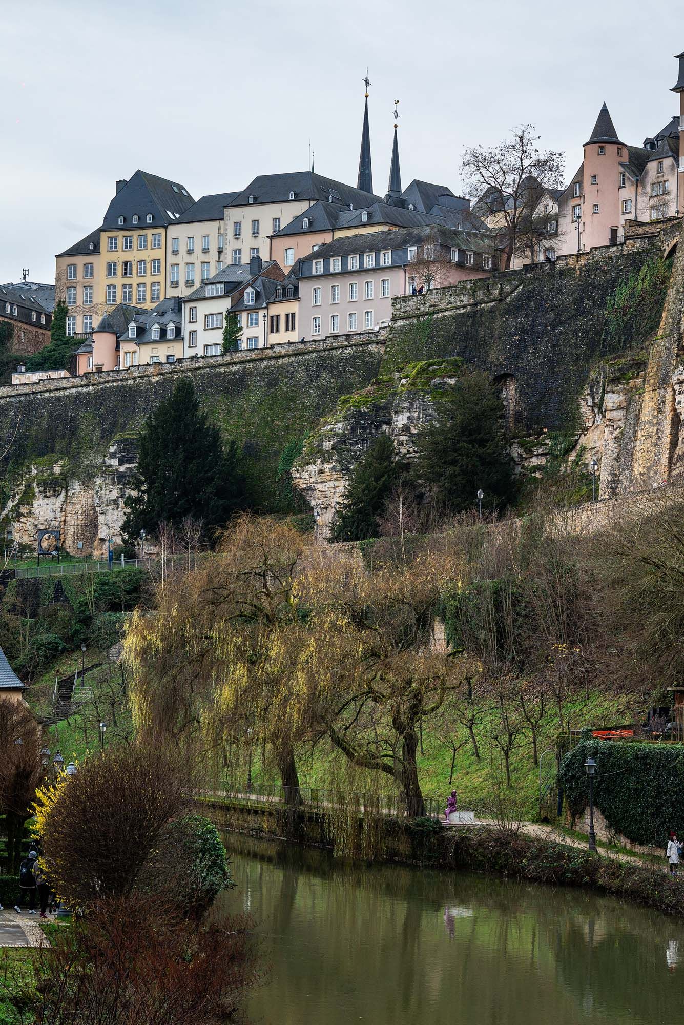 Historic buildings line the ancient fortified walls of Luxembourg City overlooking the tranquil Alzette River valley.