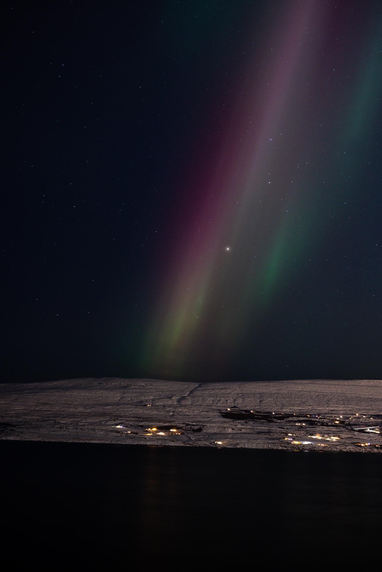 Stunning aurora borealis illuminates the night sky above a remote mining settlement in northern Greenland.