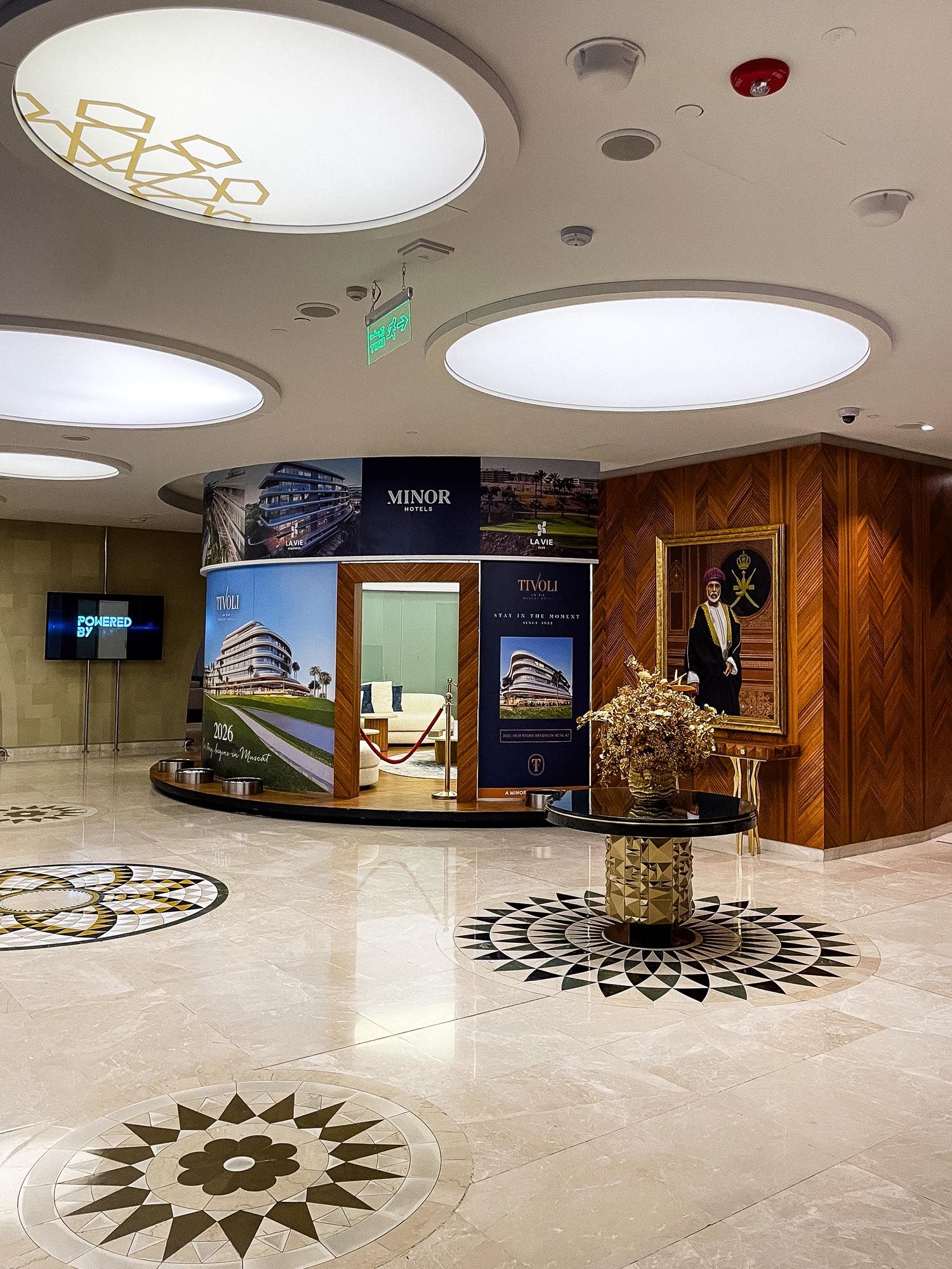 Modern lobby interior with circular ceiling lights and decorative compass rose pattern on marble floor.