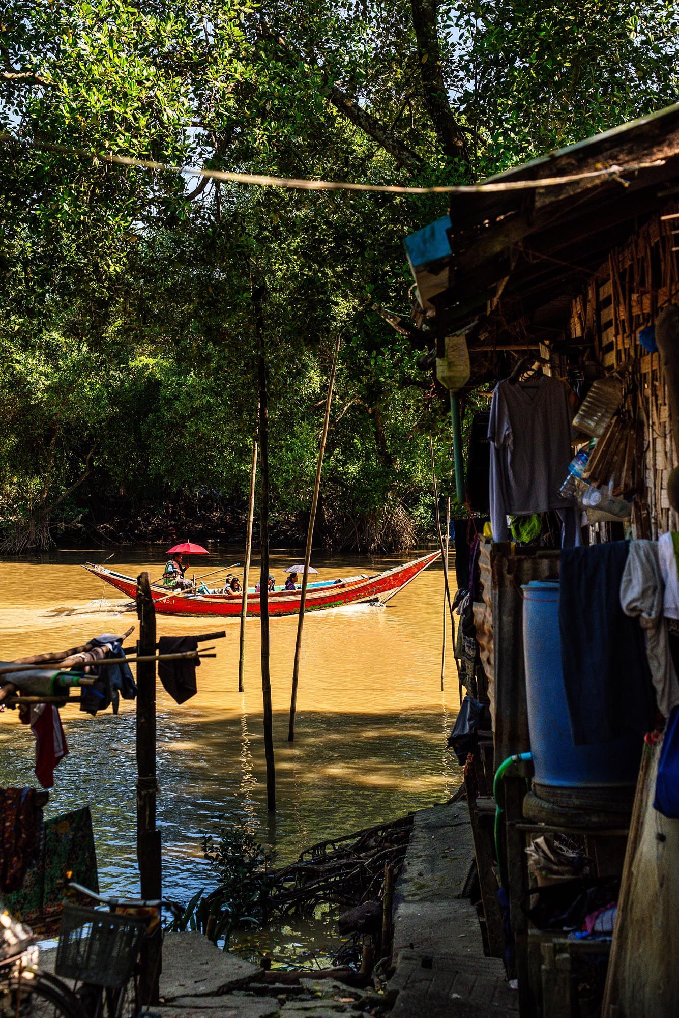 Scenic riverside camping spot with hammocks strung between trees along a muddy riverbank during summer.