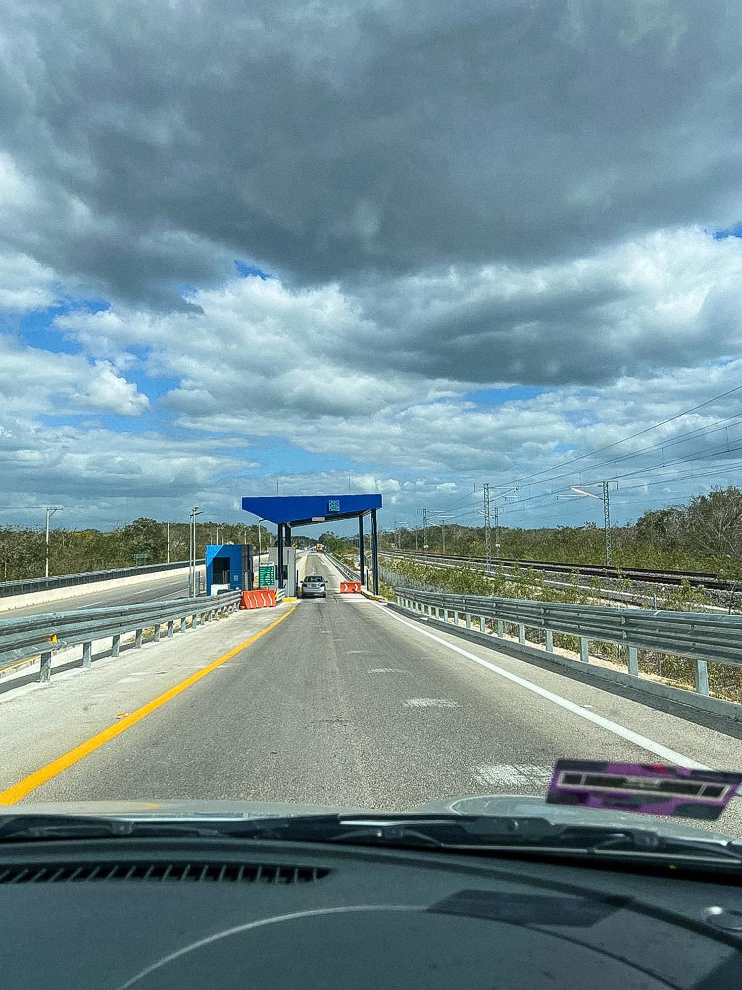 A series of dashcam views showing a highway bridge with dark storm clouds overhead and blue canopy structures along the roadway.