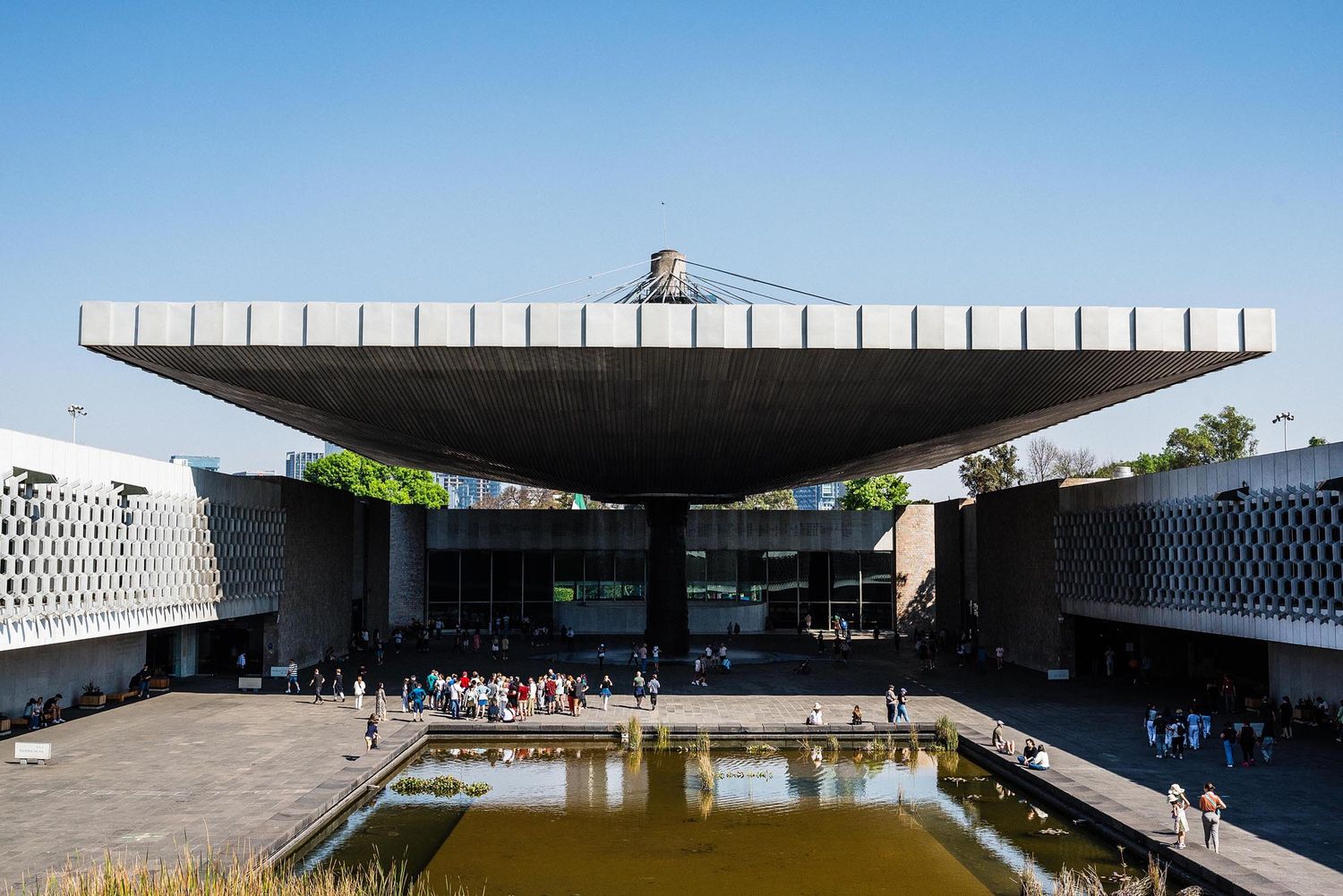 Modern minimalist architecture features a long horizontal building with reflecting pool and clean geometric lines.
