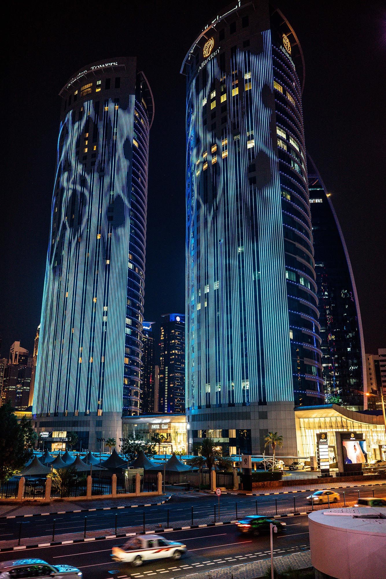 Illuminated modern skyscraper building in Qatar glows with blue lights against dark night sky in progressive sequence.
