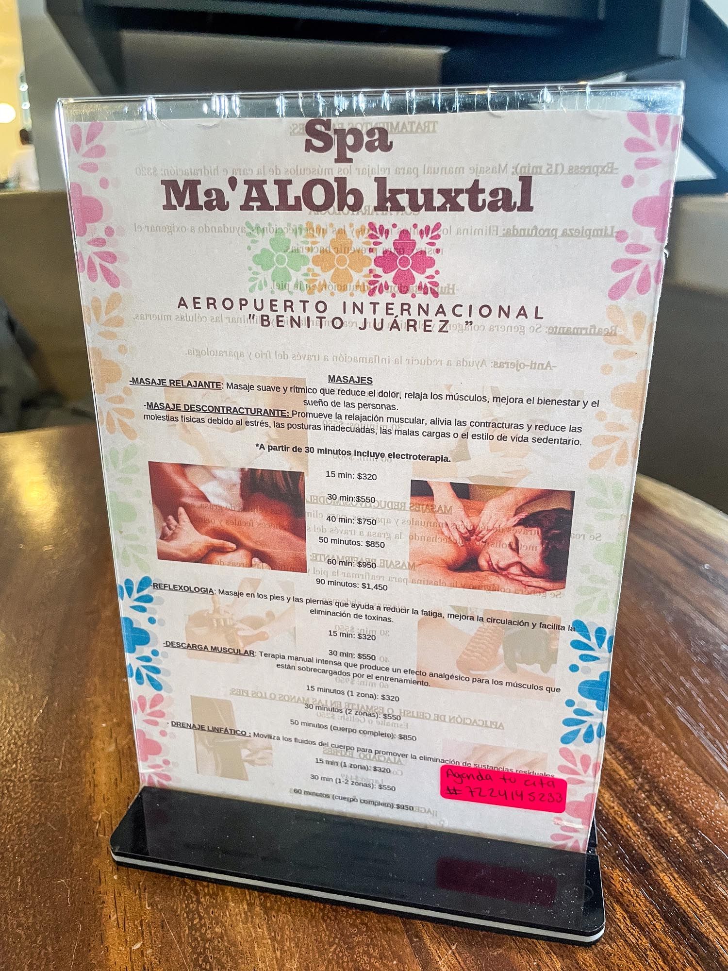 Three spa service menus displayed on wooden tables showing massage and treatment offerings at an airport location.