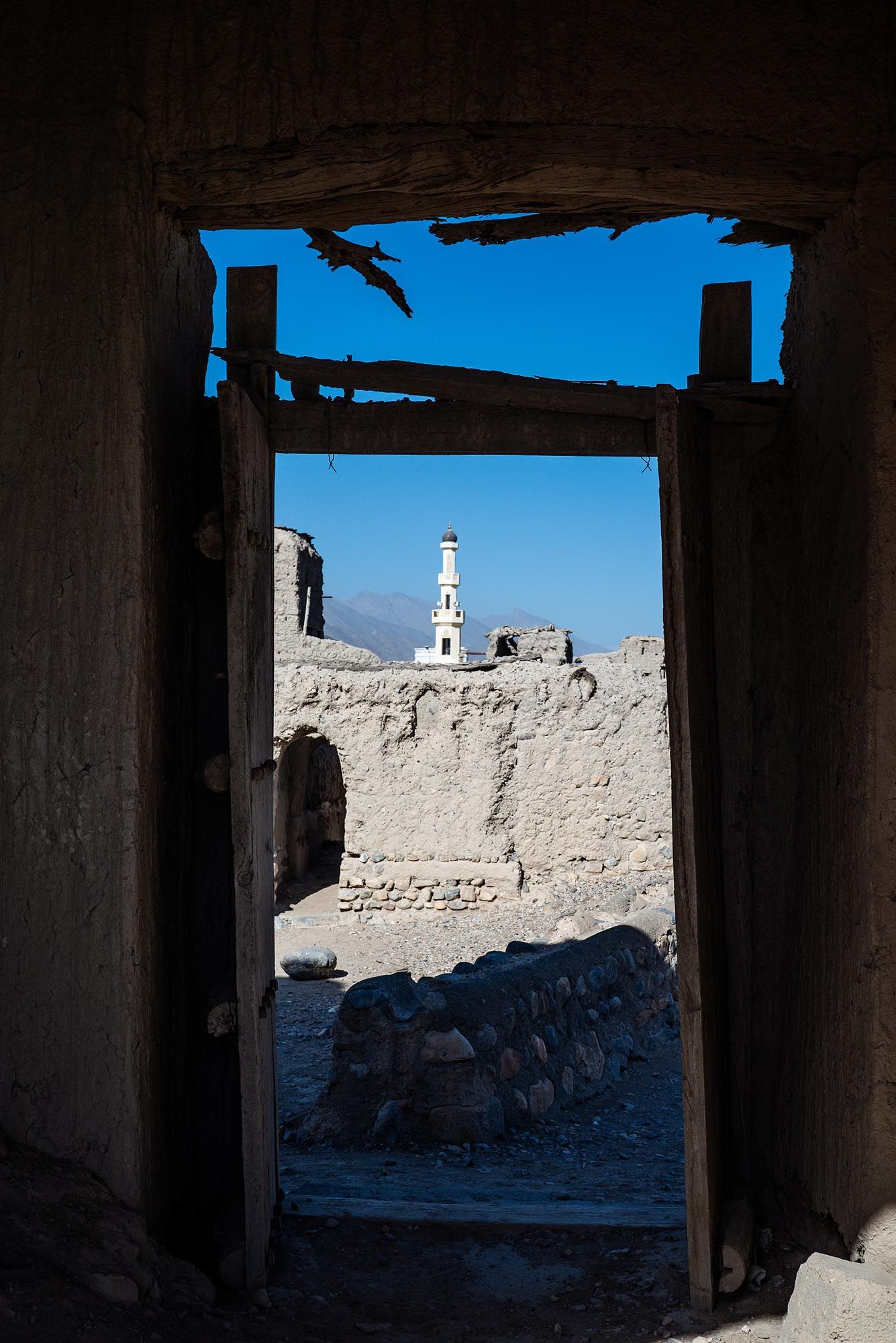View through a doorway of an old stone building showing a minaret against bright blue sky in Dubai's historic district.
