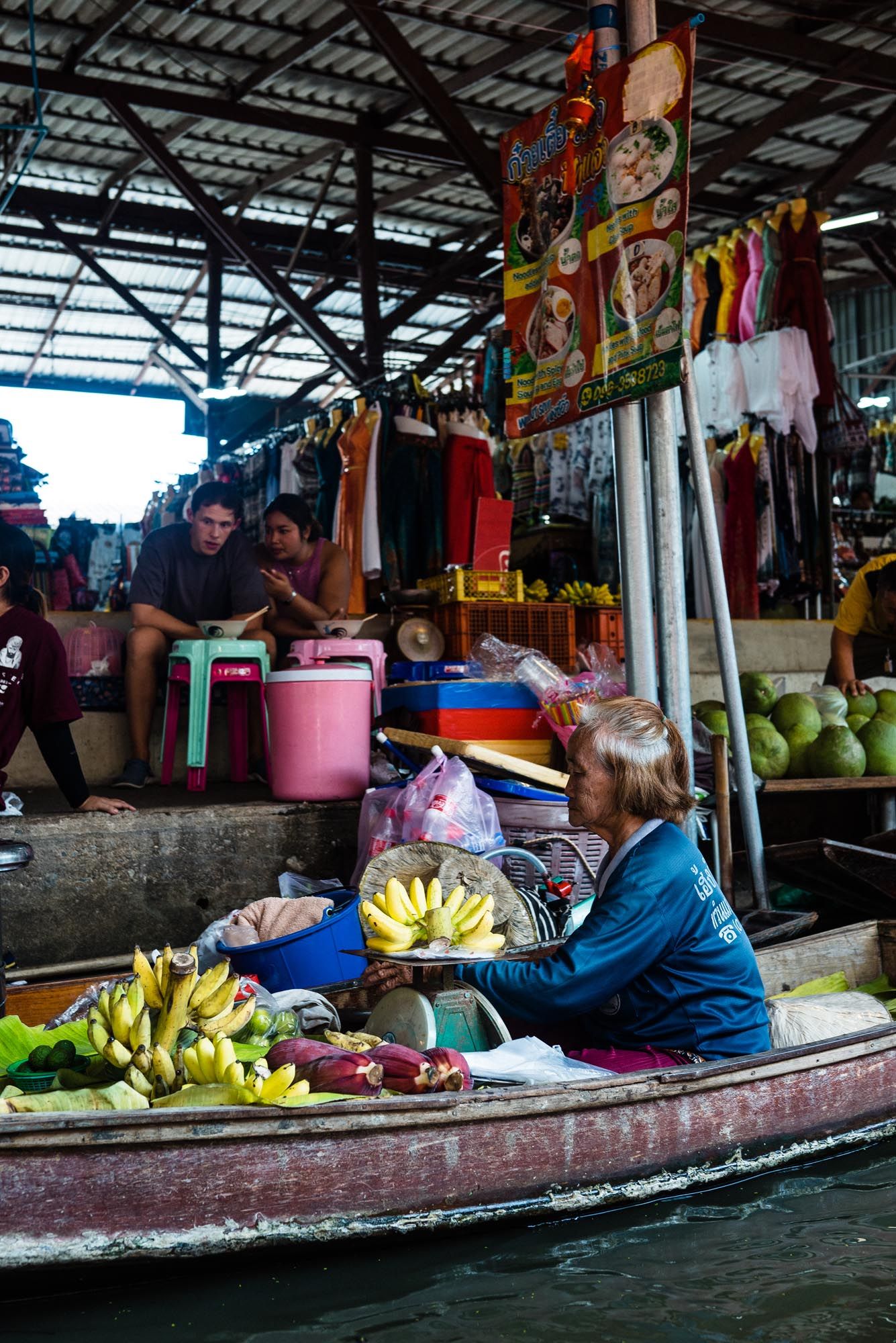 Vendors sell fresh produce and goods from wooden boats at a traditional floating market in Thailand.