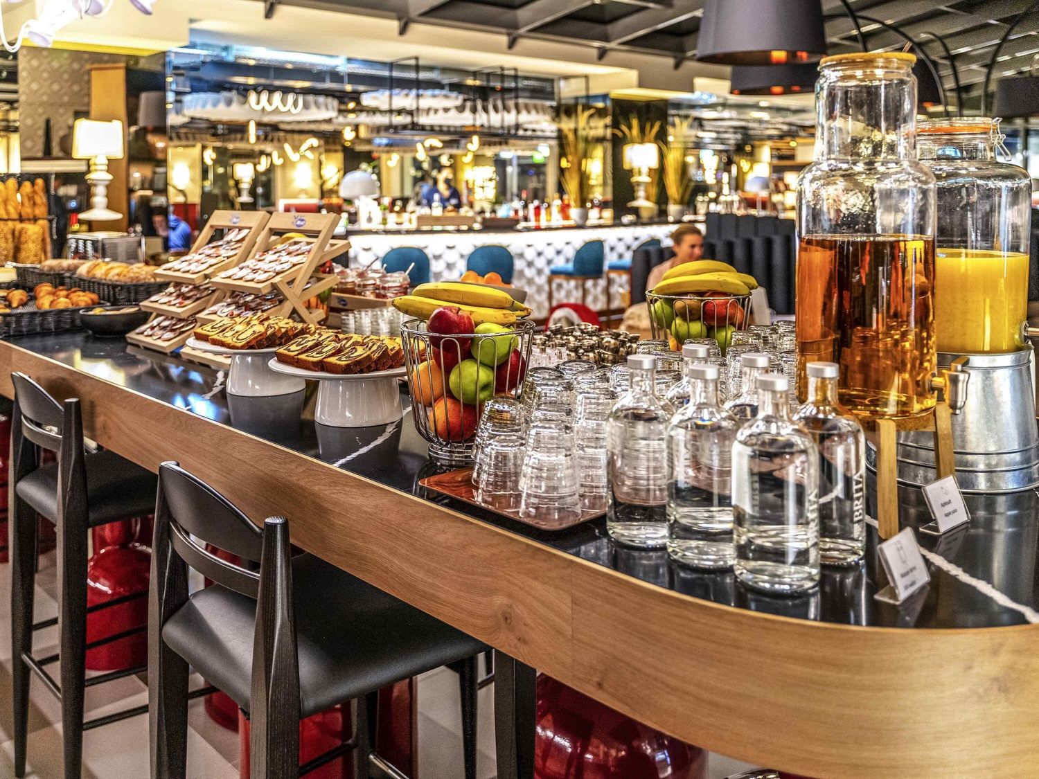 Modern bar interior with curved wooden counter and rows of glassware displayed on illuminated shelves.