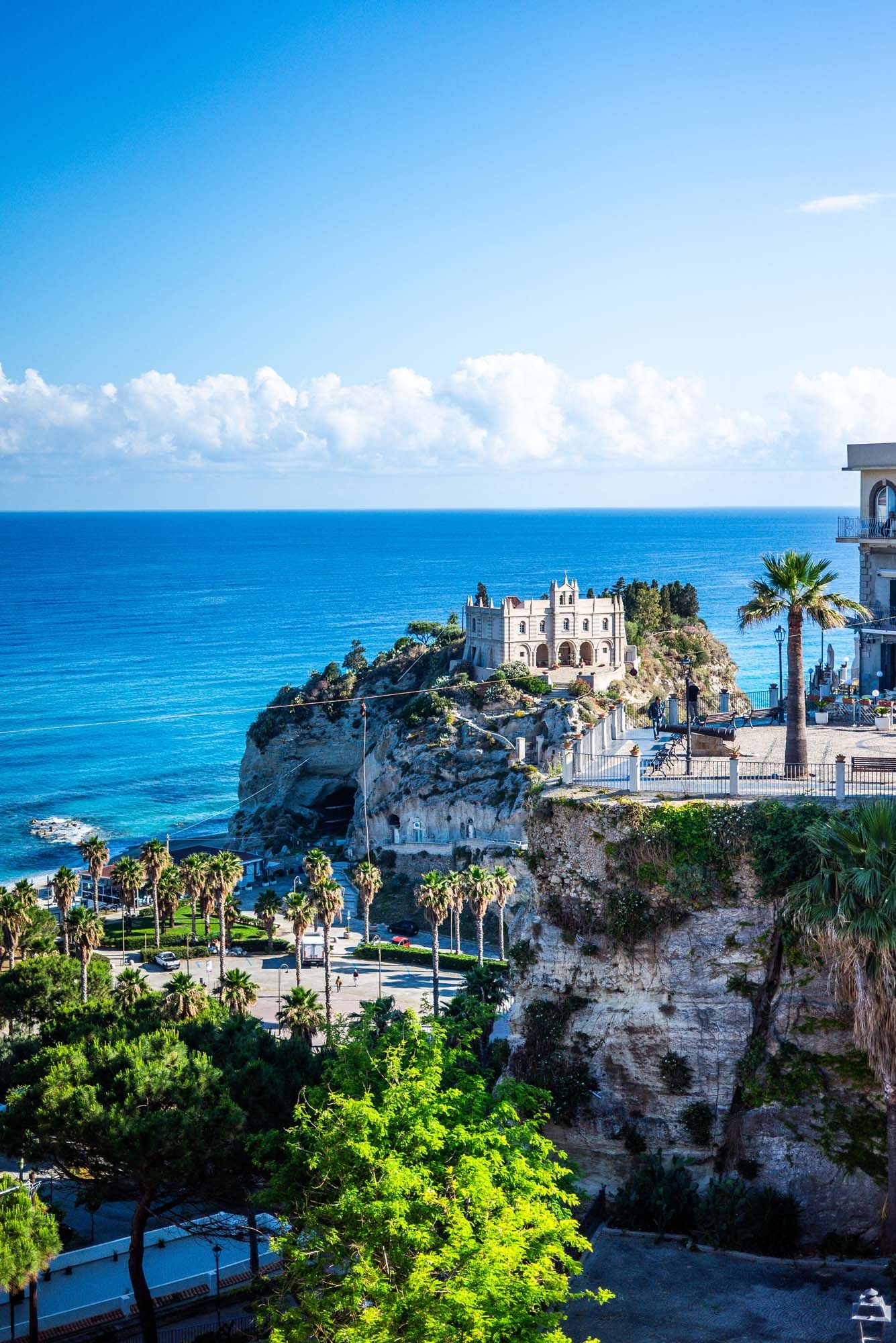 Scenic coastal view of Tropea, Italy with white buildings perched on dramatic limestone cliffs overlooking turquoise waters.