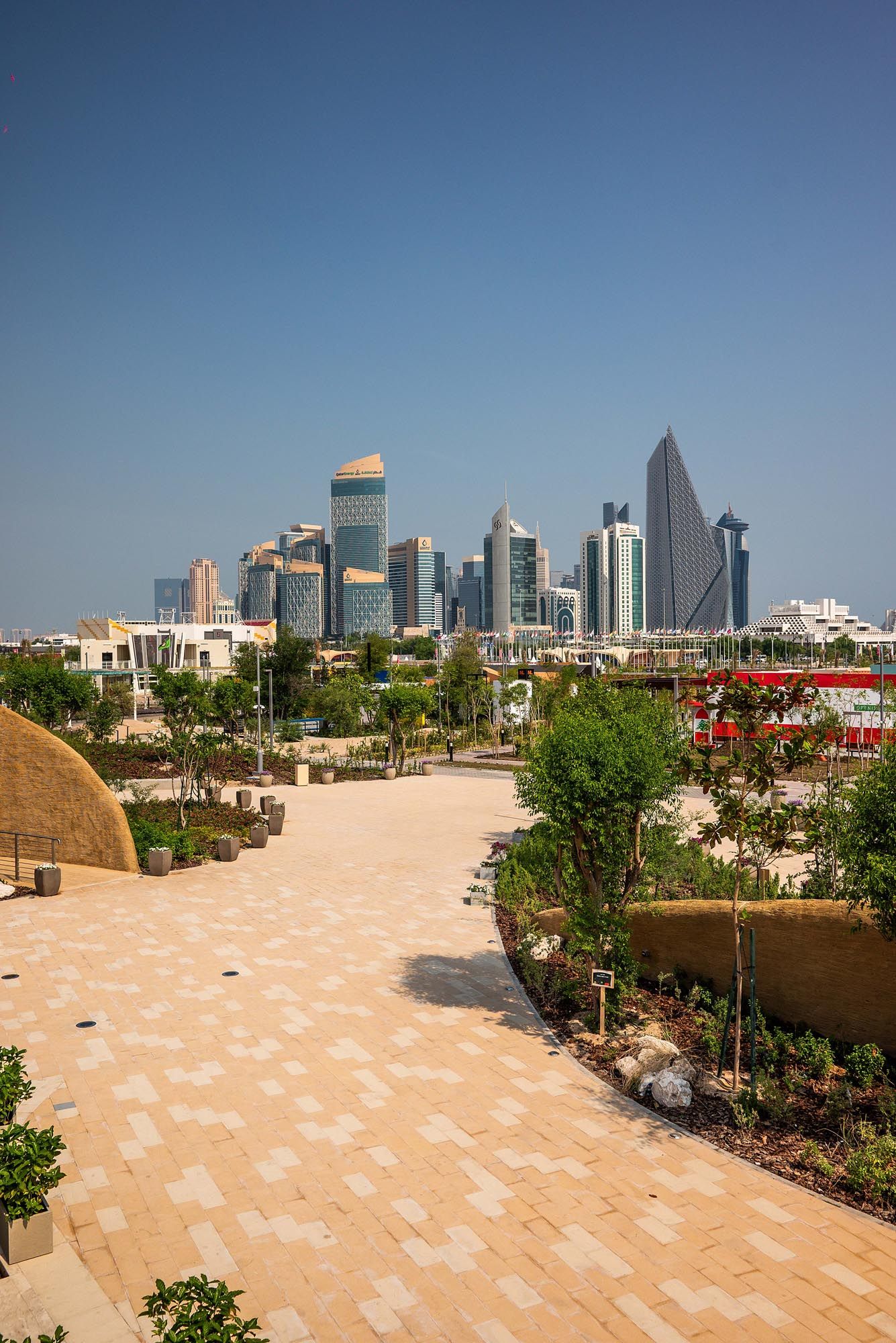 Panoramic view of Dubai's modern skyline from a rooftop terrace with tiled flooring and landscaped gardens.