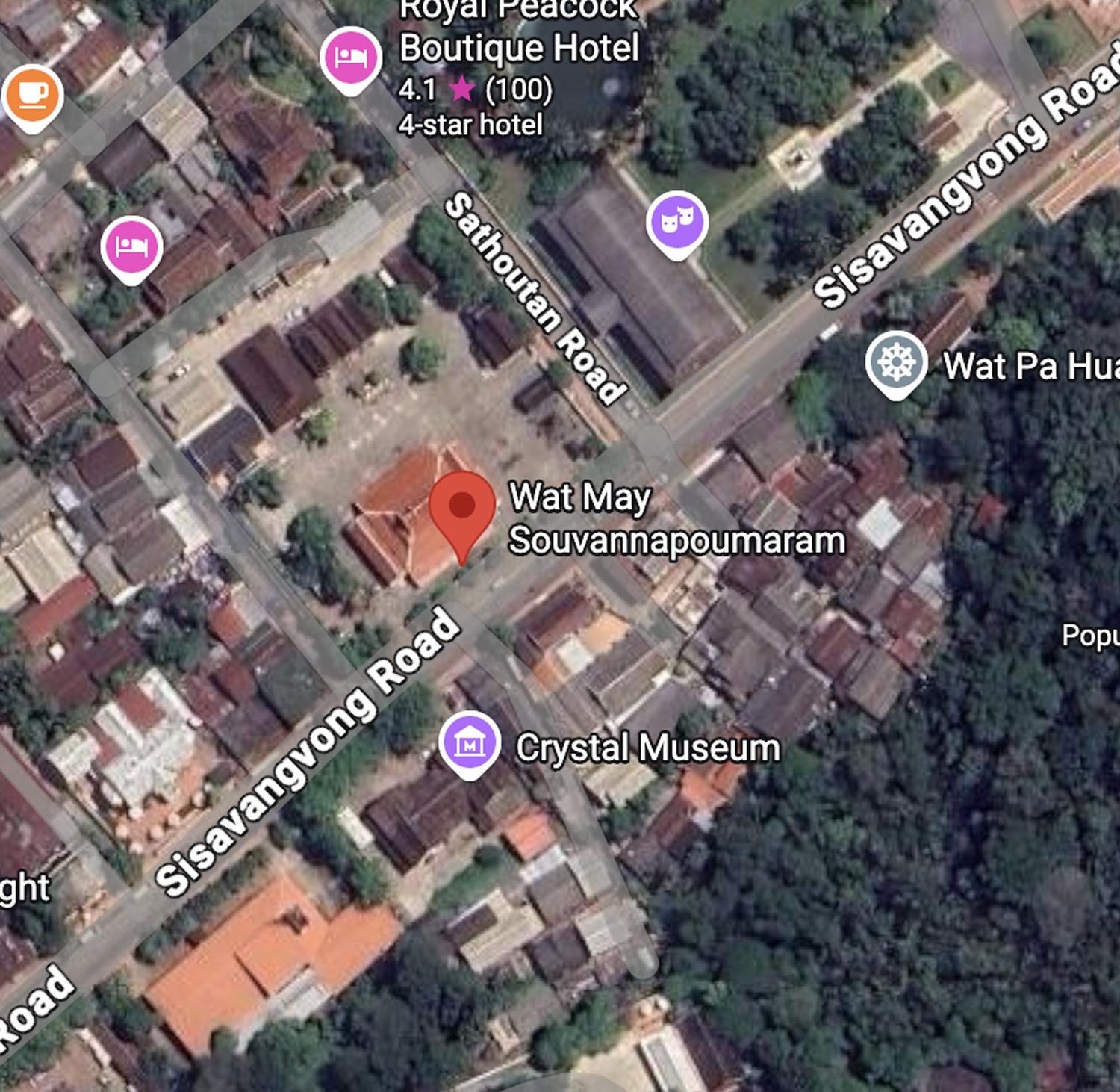 Aerial satellite view of urban buildings and roads with dense green forest area in a tropical city.
