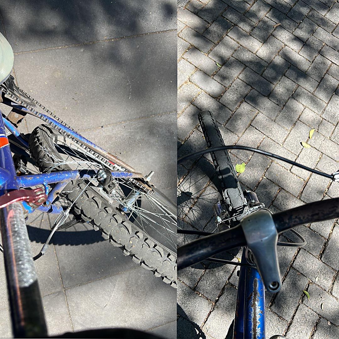 Close-up view of a broken bicycle chain and damaged gear mechanism on pavement and brick surfaces.