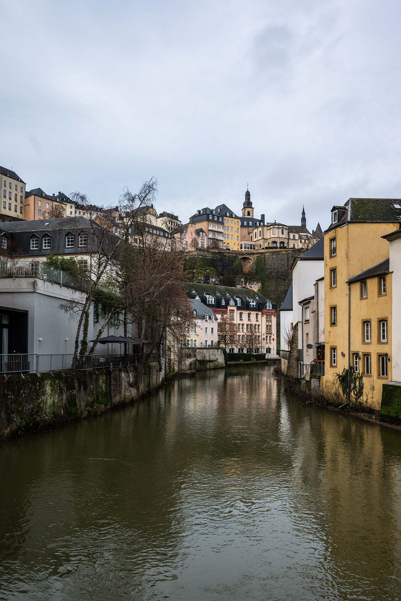 Historic buildings line both sides of a tranquil river canal in Luxembourg City's old town district.