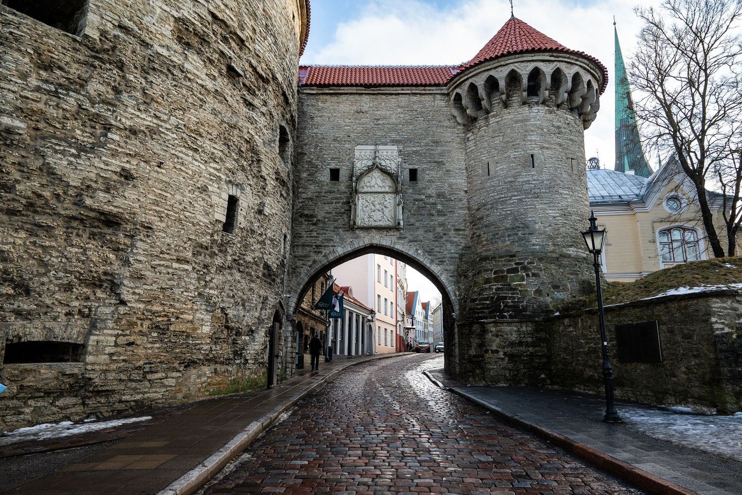 Medieval stone gate tower with arched passage on cobblestone street in historic city center.