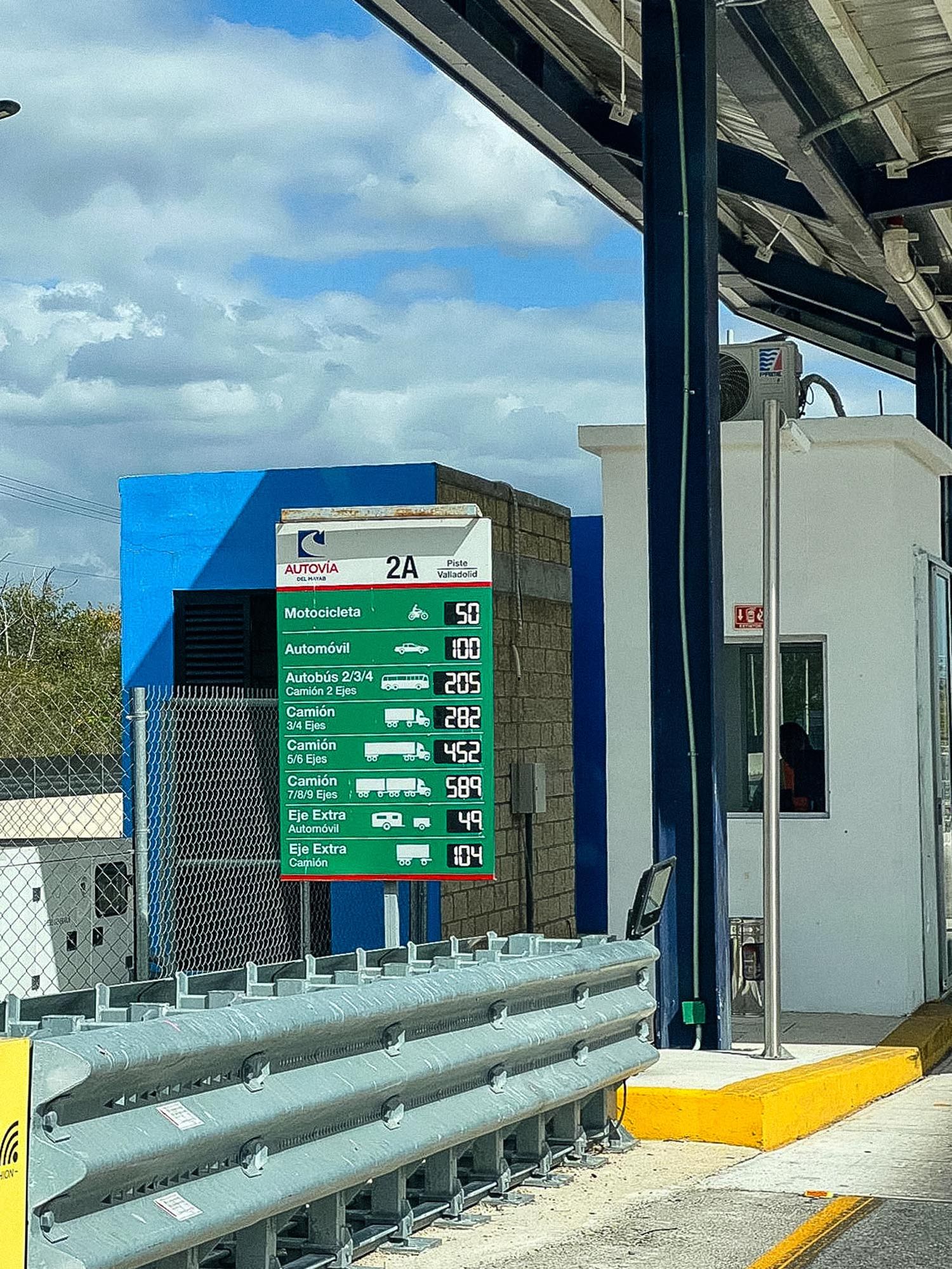 Toll booth lanes with green directional signage and safety barriers at a modern automated payment facility.