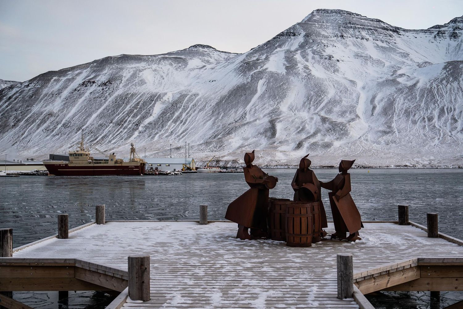 A panoramic sequence of snow-covered mountains and coastline in a rugged winter landscape.