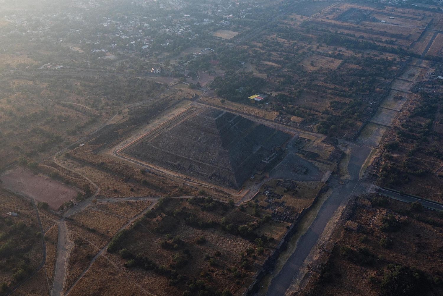 Aerial view of a rural landscape with roads and agricultural fields during hazy conditions.