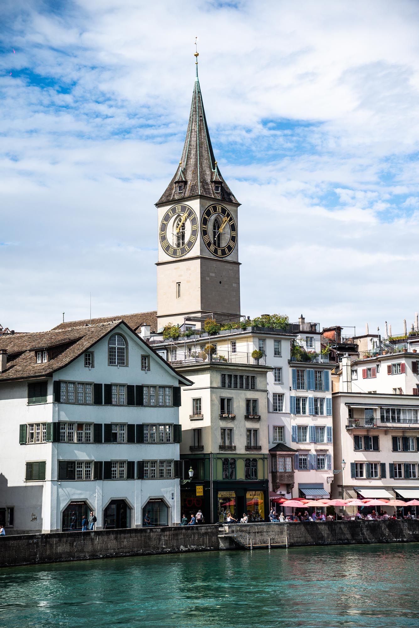 Historic waterfront buildings and church spires line the Limmat River in Zurich's old town district.