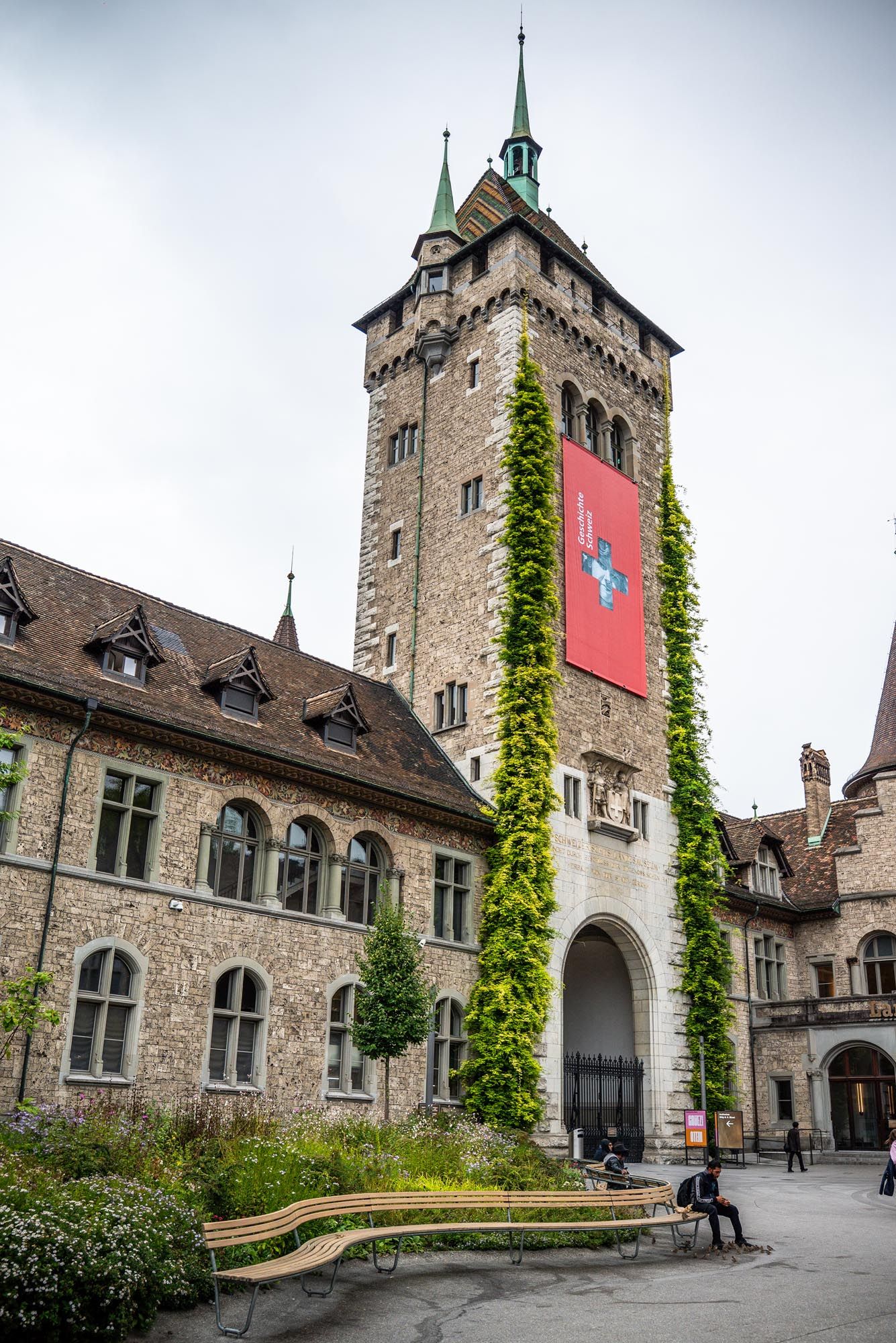 Historic Swiss National Museum building in Zurich with ivy-covered stone walls and Gothic architectural features.