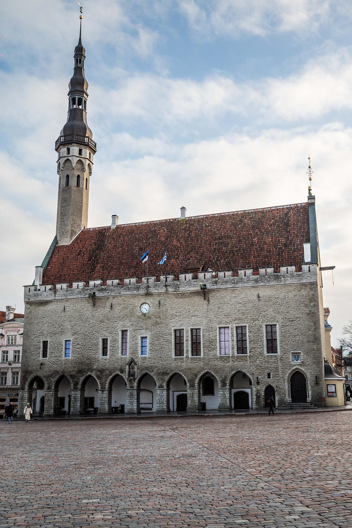 Historic Tallinn Town Hall in Estonia with its medieval stone architecture and cobblestone square under cloudy skies.