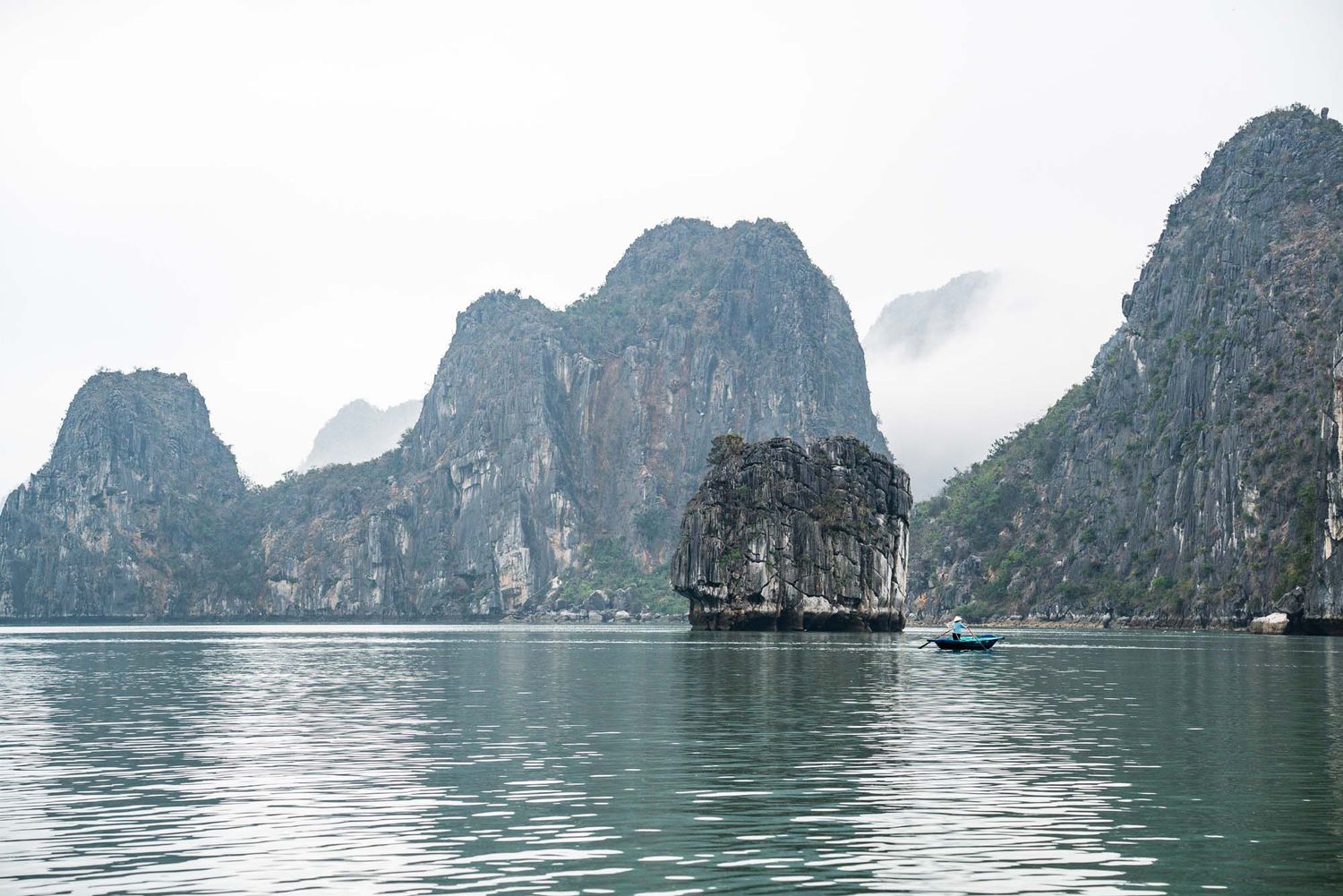 Scenic panoramic view of limestone karst formations rising from calm waters in Ha Long Bay, Vietnam.