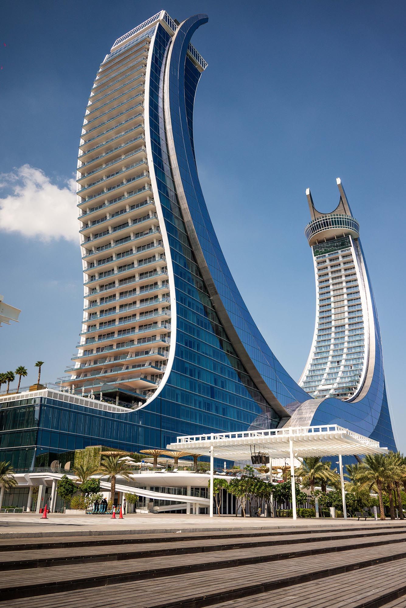 Modern curved glass skyscrapers with distinctive sail-like architecture at a waterfront development in Dubai.