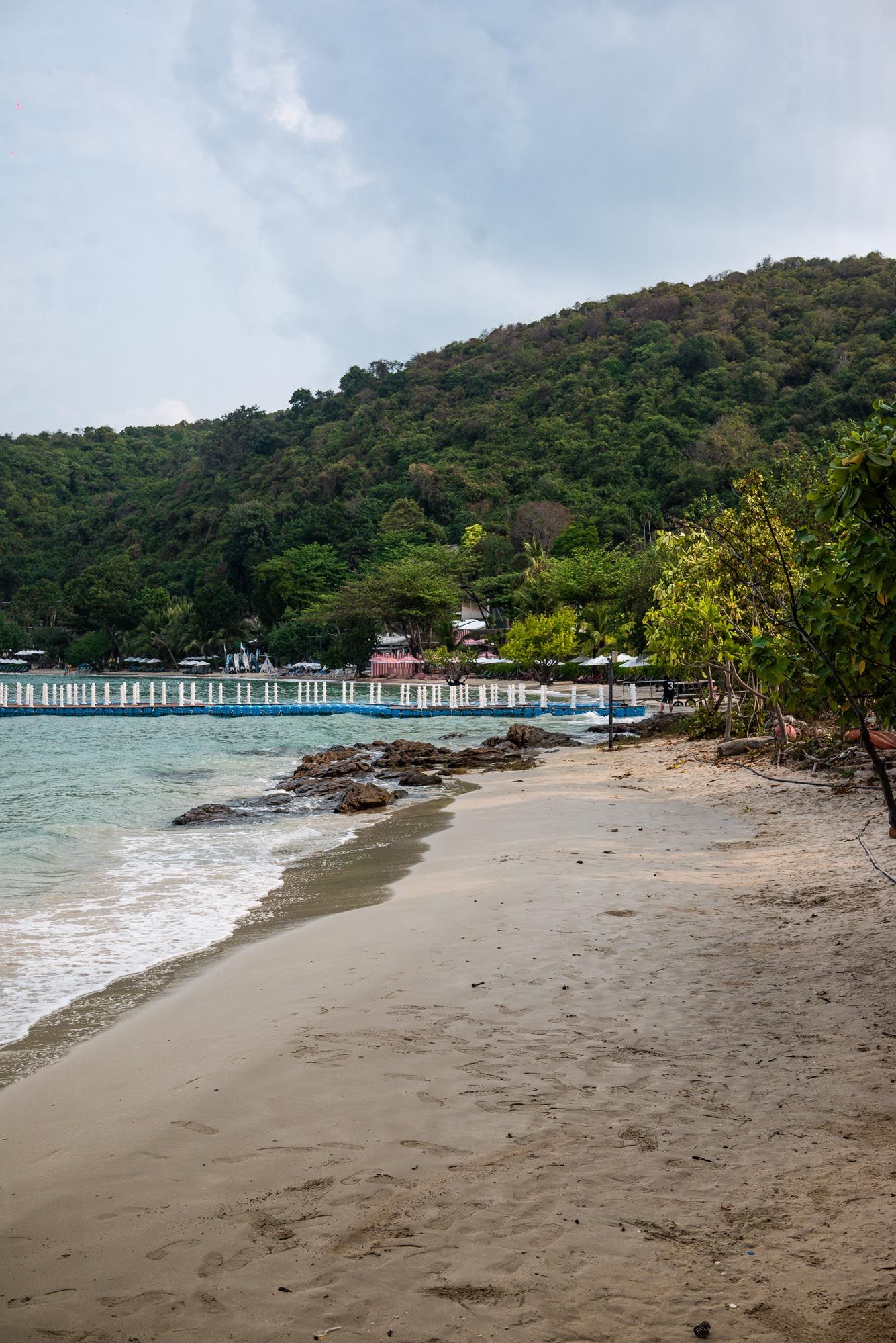Scenic beach panorama showing multiple angles of a sandy coastline with a long wooden pier and forested hills in Thailand.
