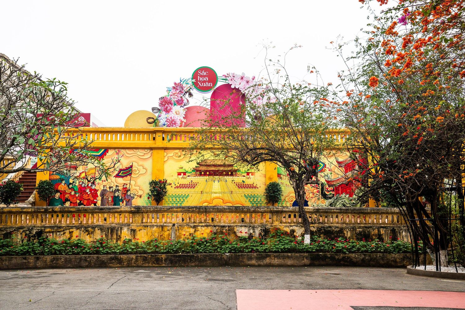 Golden yellow building with red sakura blossoms and trees creating a picturesque Asian-inspired architectural scene.