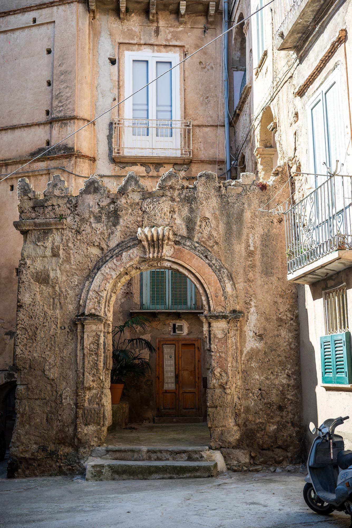 A series of five connected photos showing rustic stone archways and doorways in an old Mediterranean building facade.
