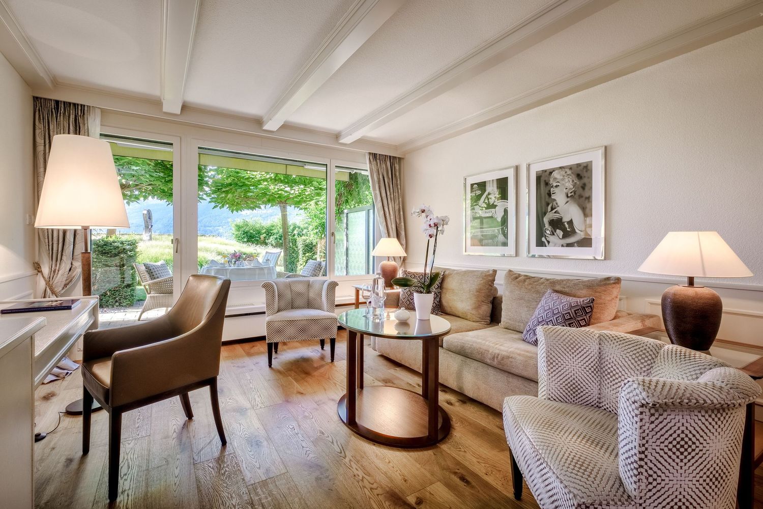 Modern living room with white walls features plush seating, large windows, and natural light streaming in.