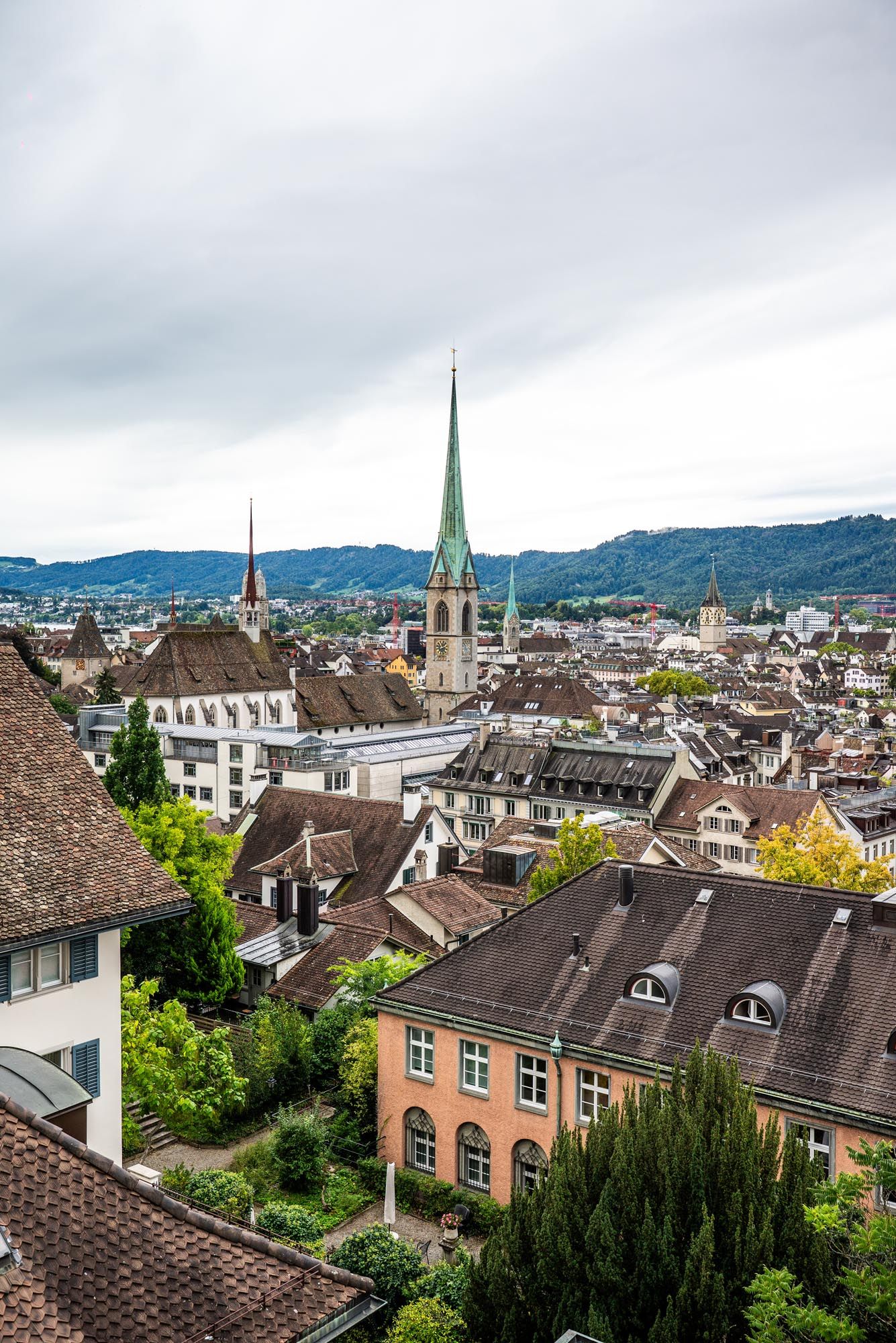 Panoramic aerial view of Zurich's historic city center with traditional architecture and church spires against cloudy skies.