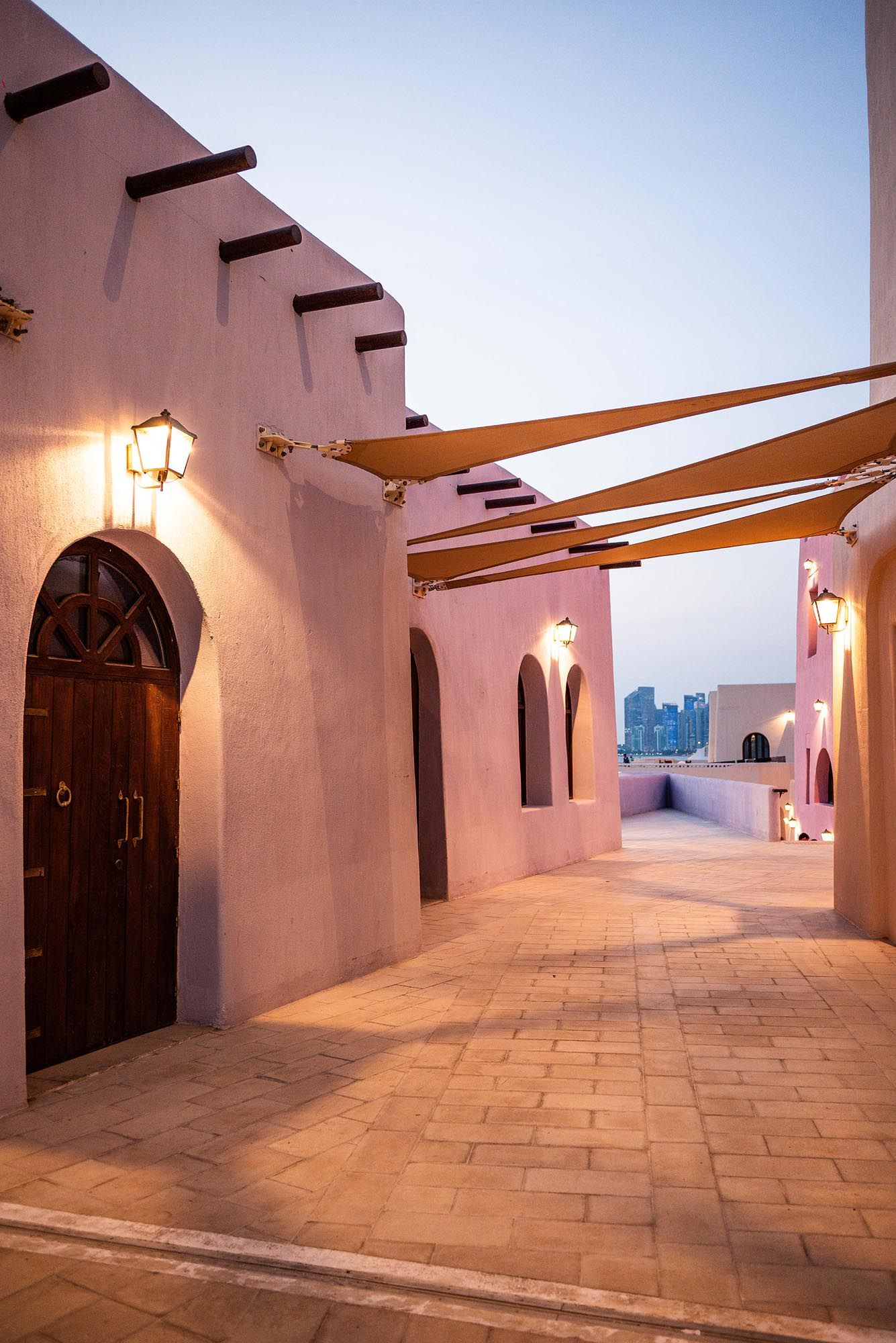Architectural hallway with white stucco walls, wooden beams, and stone flooring in traditional Middle Eastern style.