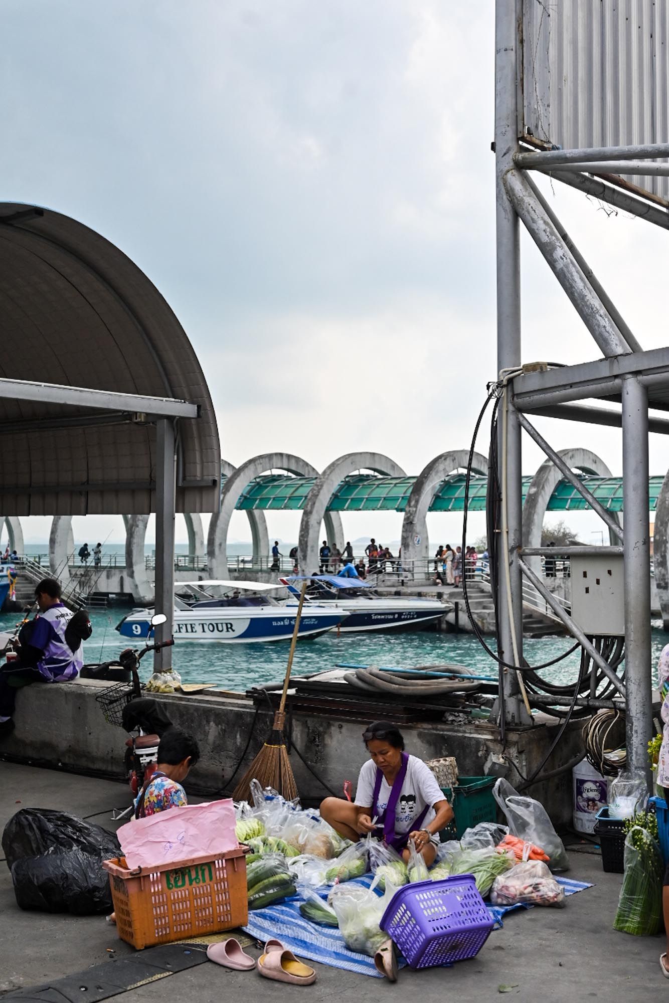 Homeless encampment with tents and belongings set up under a covered area near a swimming pool.