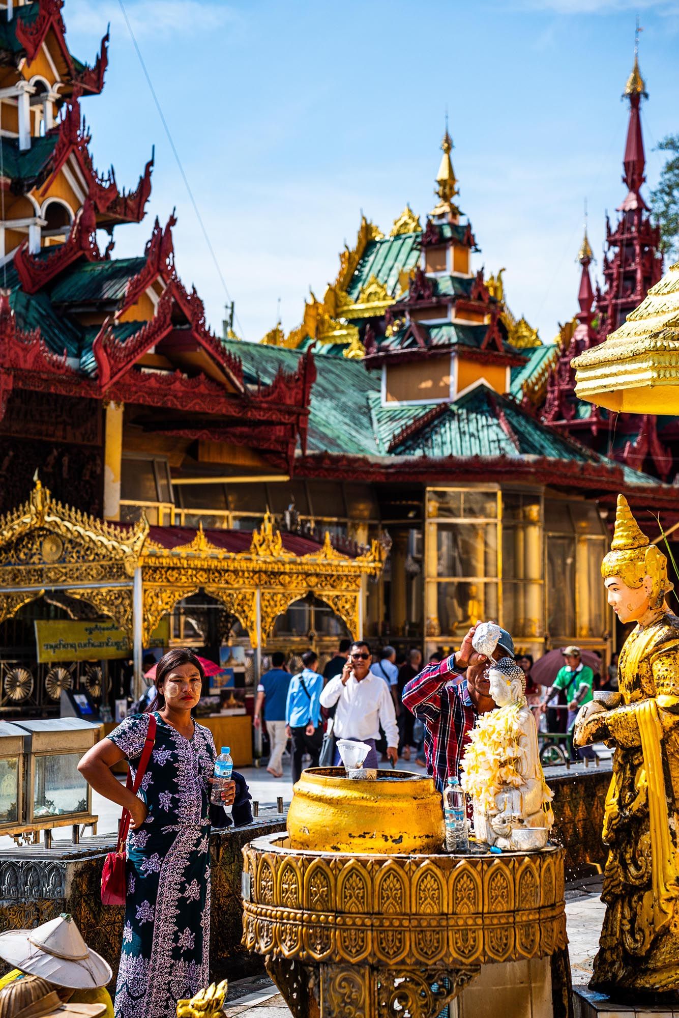 Visitors explore ornate Buddhist temples with golden spires and traditional architecture in Myanmar.