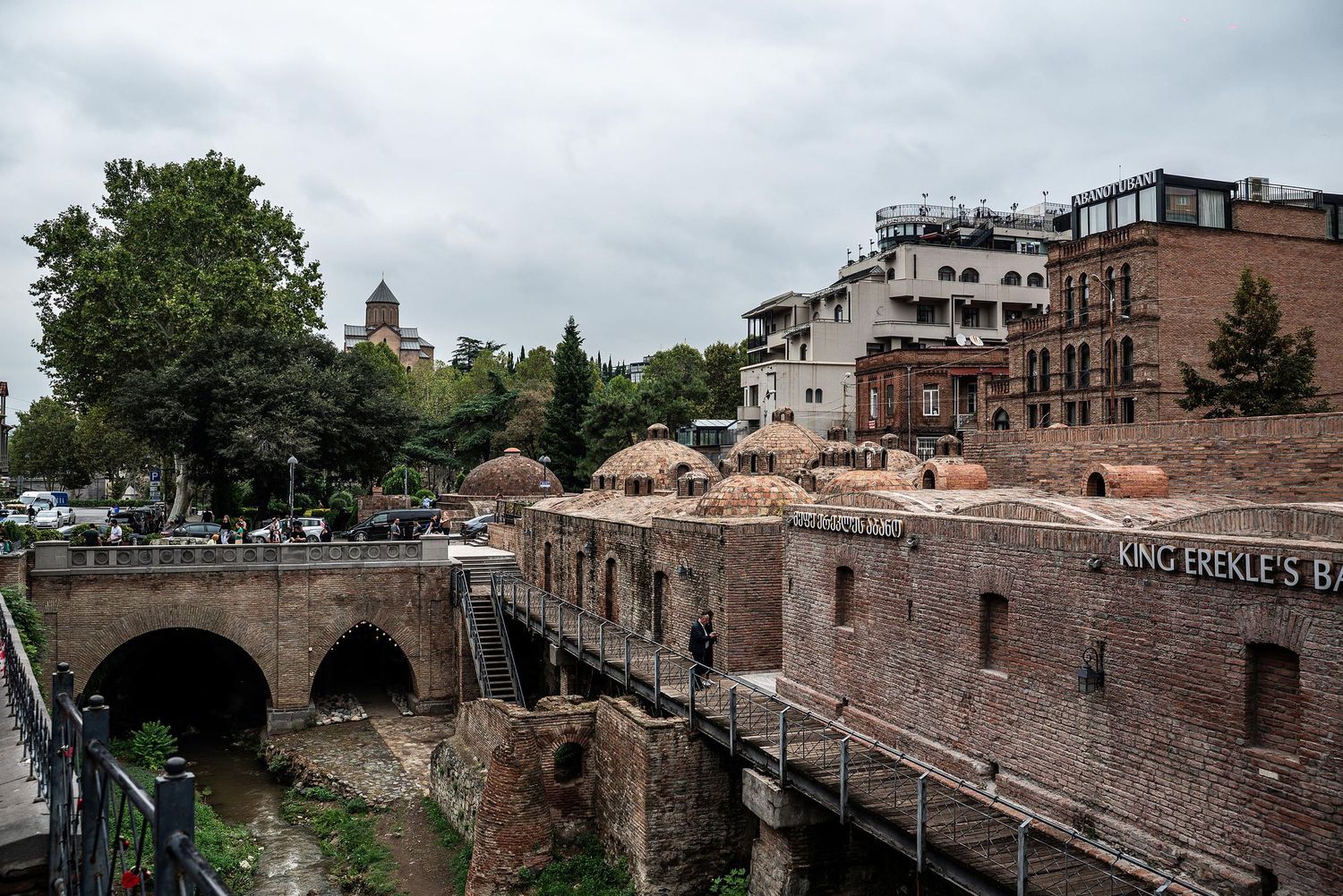 Ancient stone arches and historic architecture line a canal in Rome's historic district under cloudy skies.