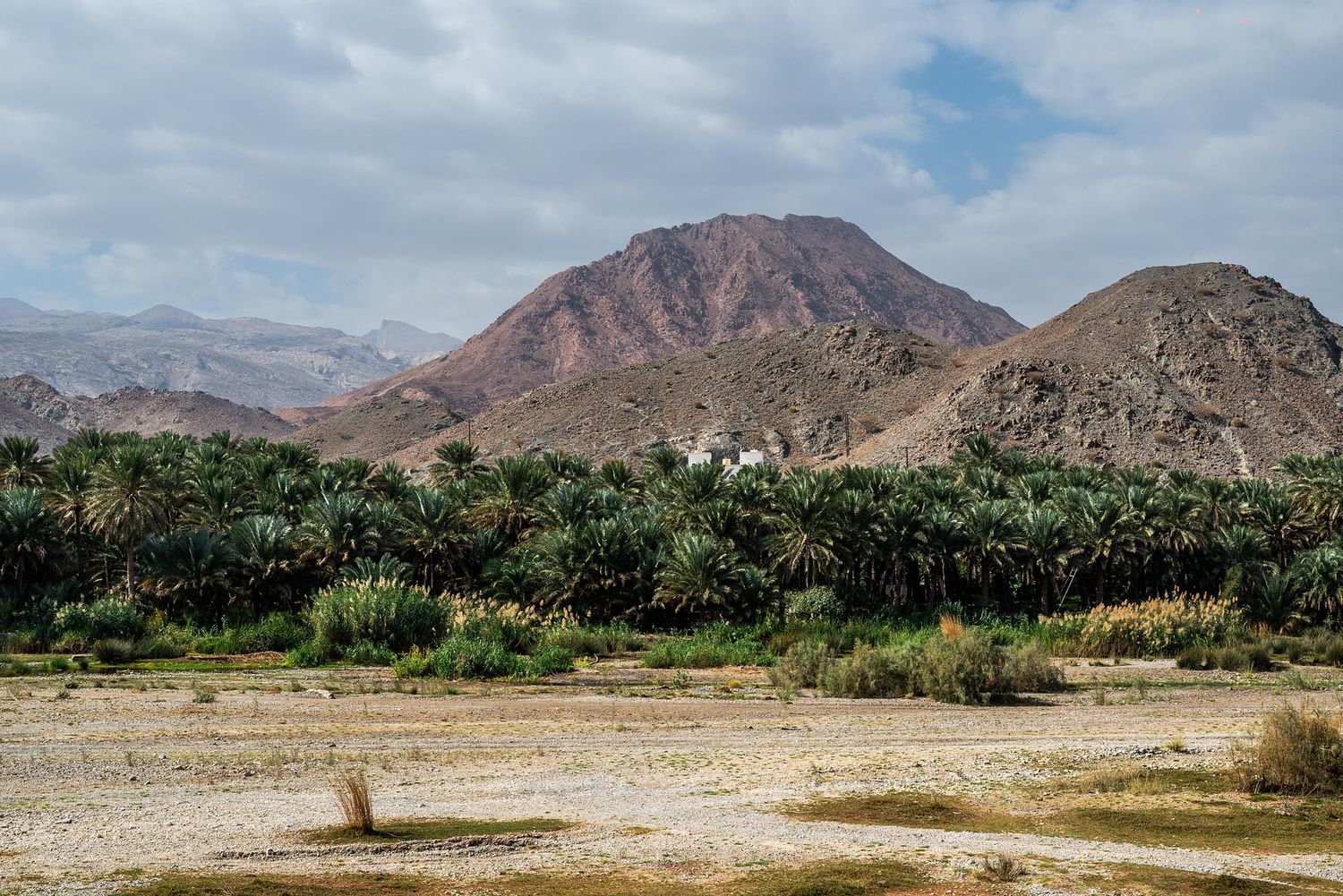 A panoramic view of rugged desert mountains and arid landscape stretches across the horizon under a partly cloudy sky.