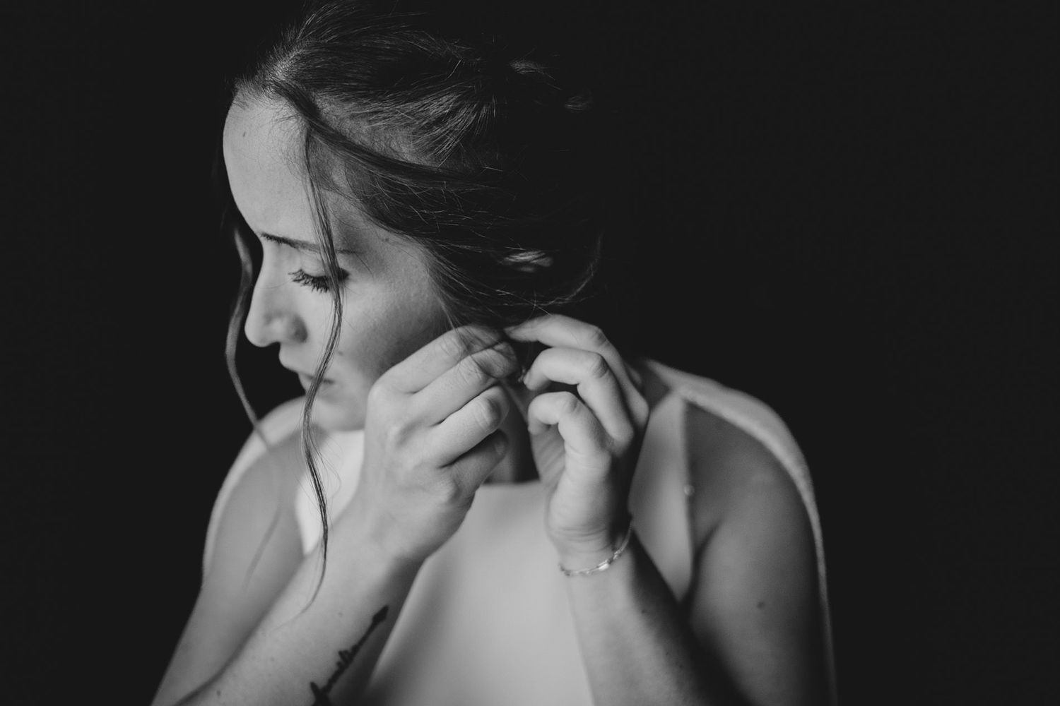 Novia colocándose los pendientes durante los preparativos de su boda en Asturias en un retrato en blanco y negro