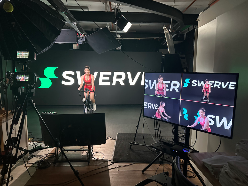 Wide shot of the studio with an instructor from Swerve fitness premium cycling workouts live streaming in front of the 20'x8' LED wall