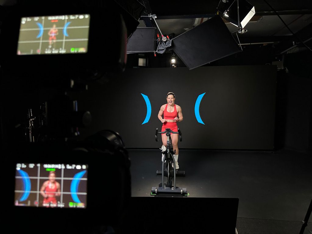 An instructor from Swerve fitness premium cycling workouts live streaming fitness to gyms around the world in front of the 20'x8' LED wall
