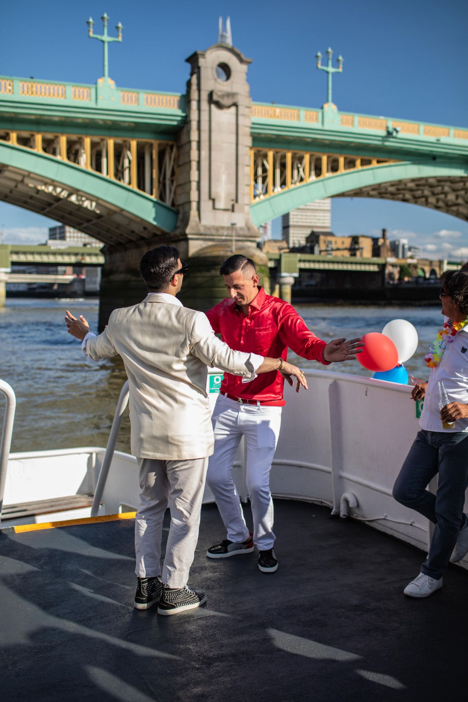 People dancing on a boat party on the River Thames with Southwark Bridge in the background, London.