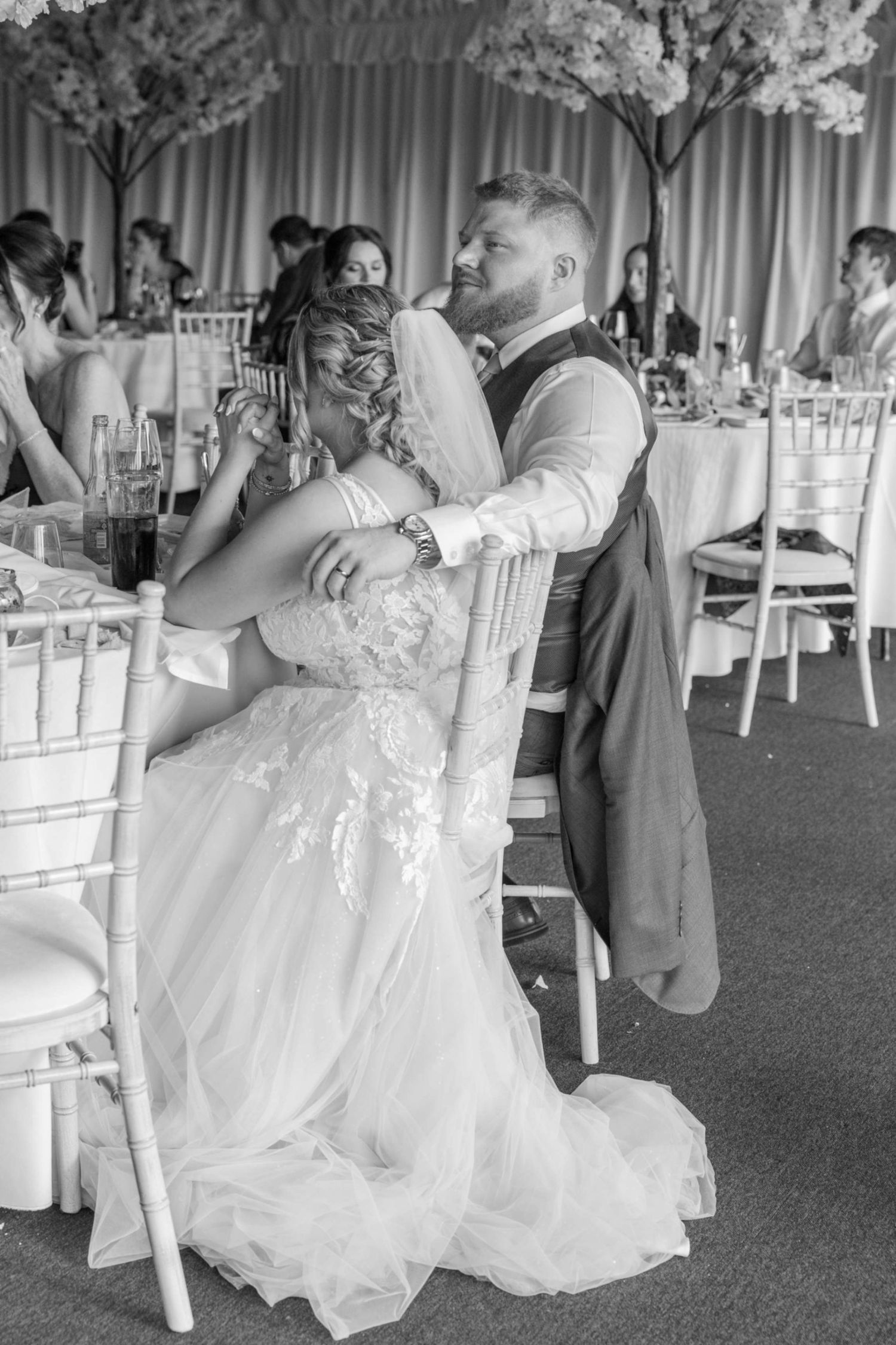 Black and white photo of a bride and groom sharing a tender moment at their wedding reception.