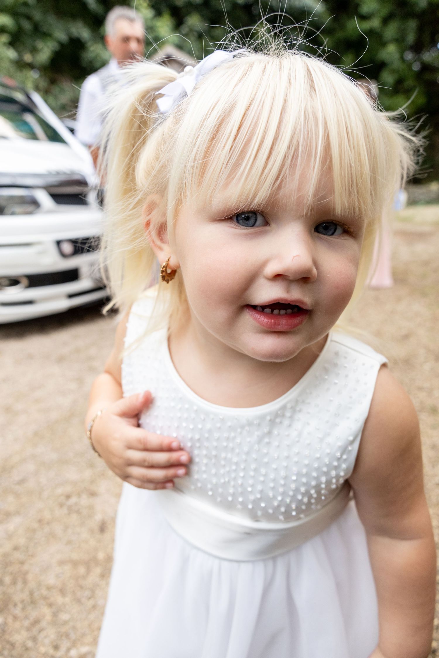 A series of photos showing a child in a white dress with polka dot collar smiling and playing outdoors.