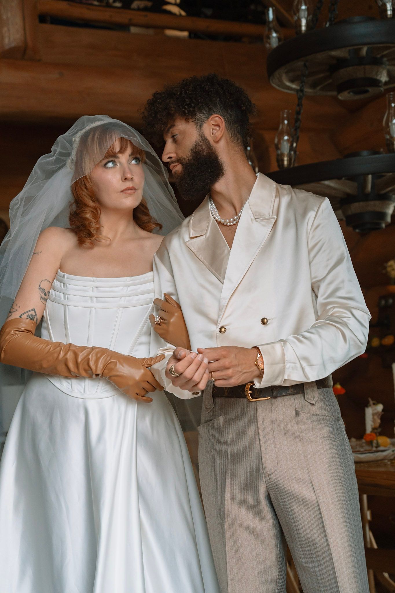 A couple in wedding attire share an intimate moment, the bride in white while the groom wears a cream-colored suit. Romantic and intimate