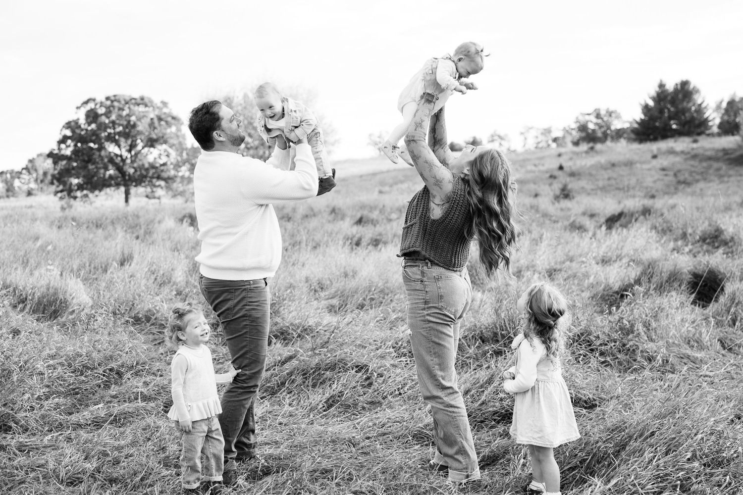 Black and white series of a family walking together through a grassy hillside.