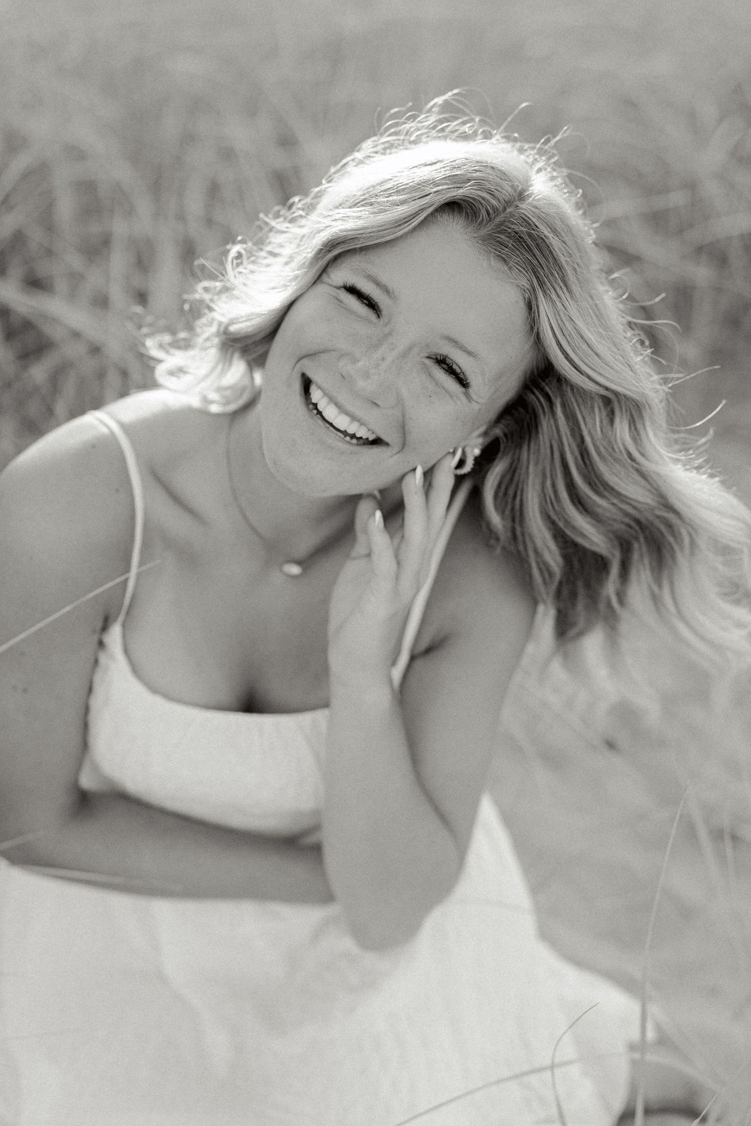 A black and white portrait showing joyful expression in natural outdoor setting.