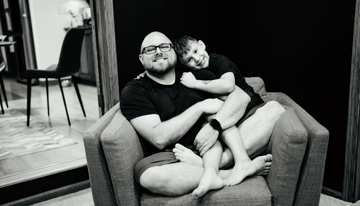 Casual family moment captured in black and white on living room couch.