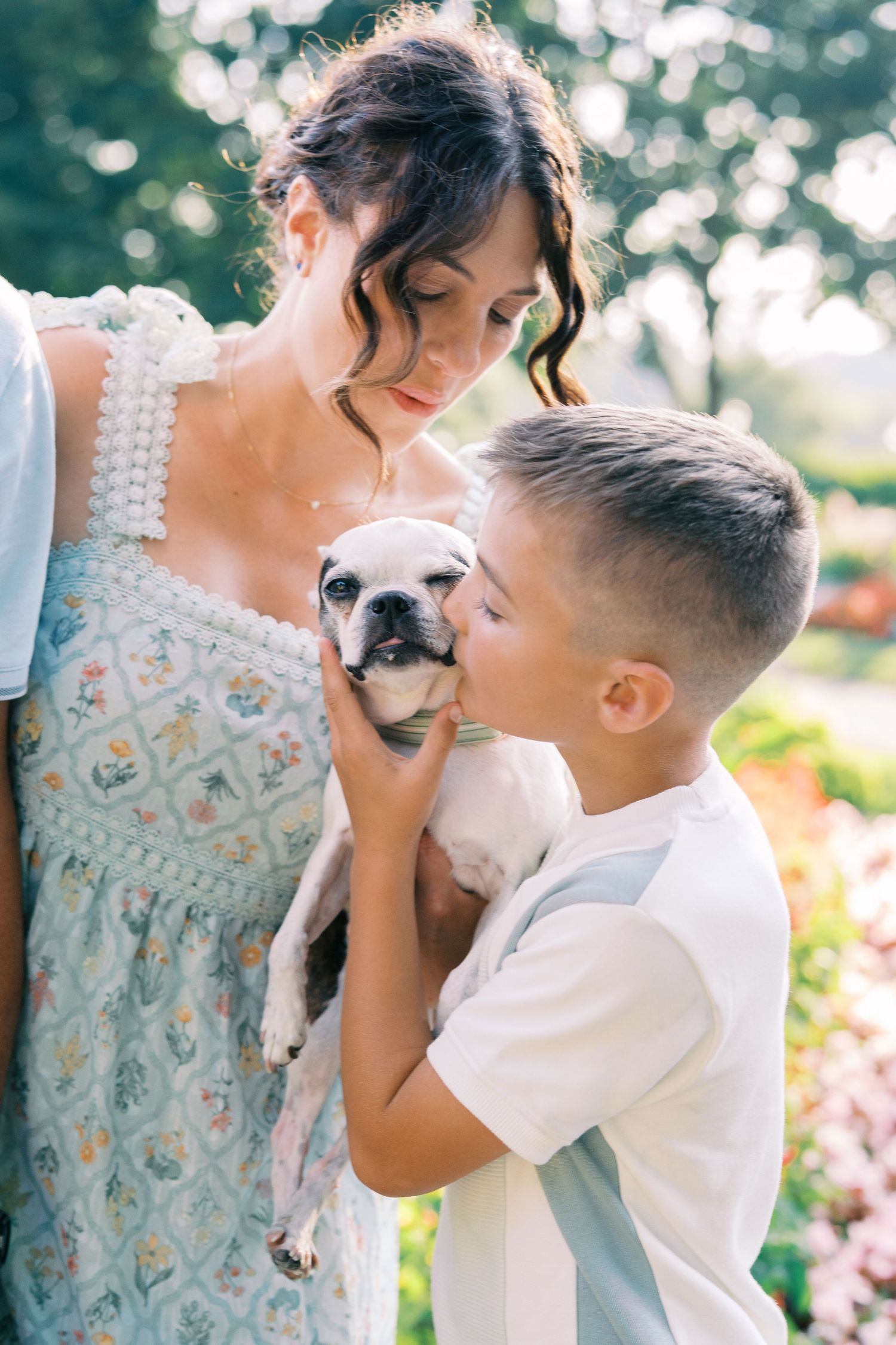 Sweet moment with a French Bulldog puppy in a sunny garden setting.