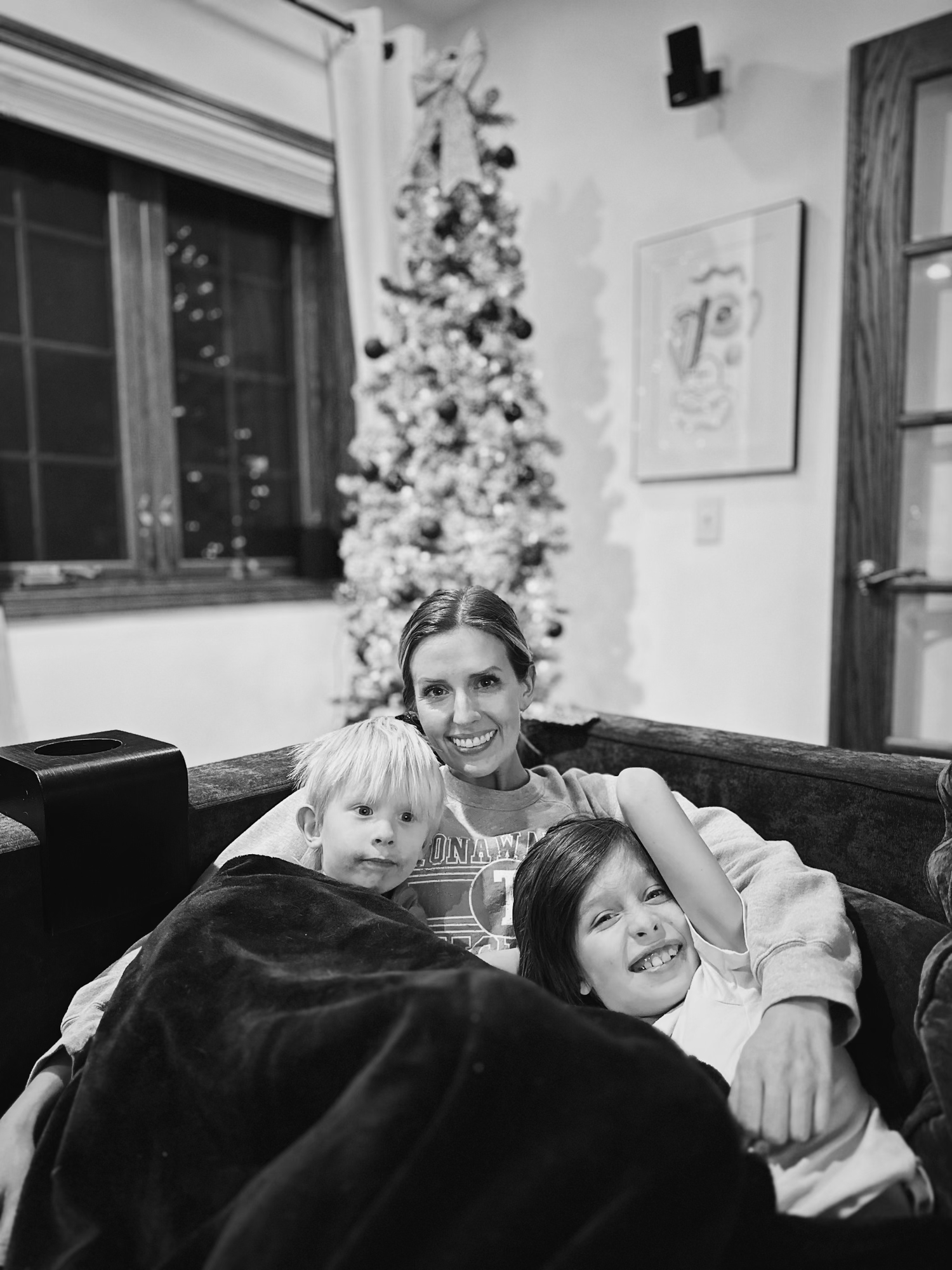 Candid black and white family moments captured on couch during holidays.