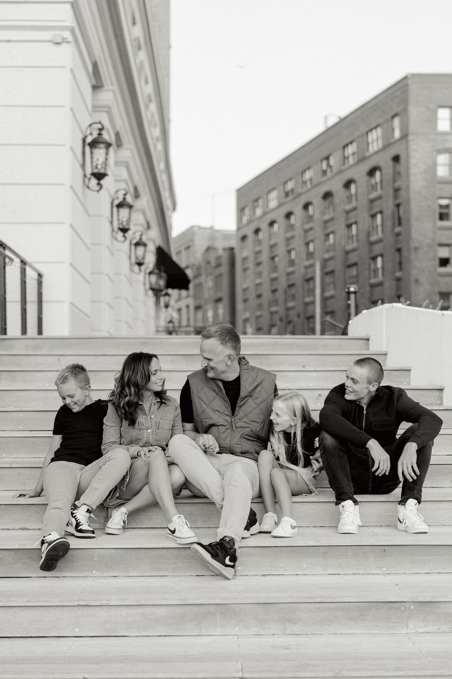 Family sitting together on urban steps in black and white portrait.