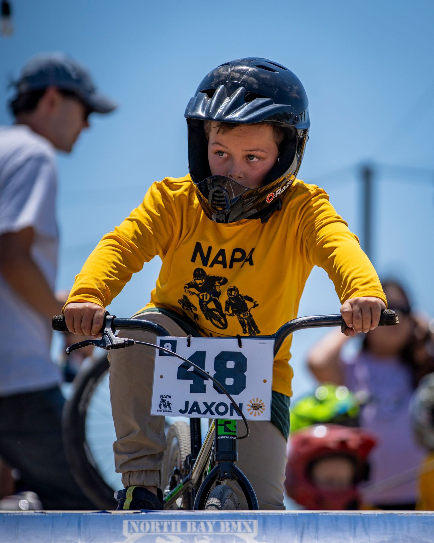 Young BMX rider in yellow jersey with race number 48 at starting position.